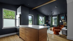 A modern kitchen with a wooden island, a refrigerator, and a dining area with a table and chairs. - Wonderland Unit A · Sleeps 12, Hot Tub & BBQ (Austin)