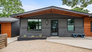 A modern two-story building with a flat roof, large windows, and a wooden overhang. - Wonderland Unit A · Sleeps 12, Hot Tub & BBQ (Austin)