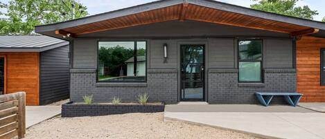 A modern two-story building with a flat roof, large windows, and a wooden overhang.