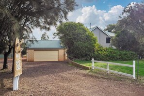 Ein Wohnhaus mit Garage, umzäunter Garten und einem Schild mit einer Grundstücksnummer.