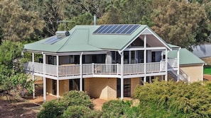 Ein zweistöckiges Haus mit Balkon, Solaranlage auf dem Dach und einem Backsteinfundament.