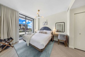 A hotel room with a bed, a desk, a chair, a large window, and a city view. - Modern Wynwood 1BR | Rooftop Pool & Gym (Miami)