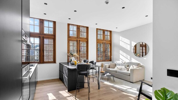 A modern kitchen with a dining area, large windows, and a round mirror. - Maison Grand-Place 2 (Brussels)
