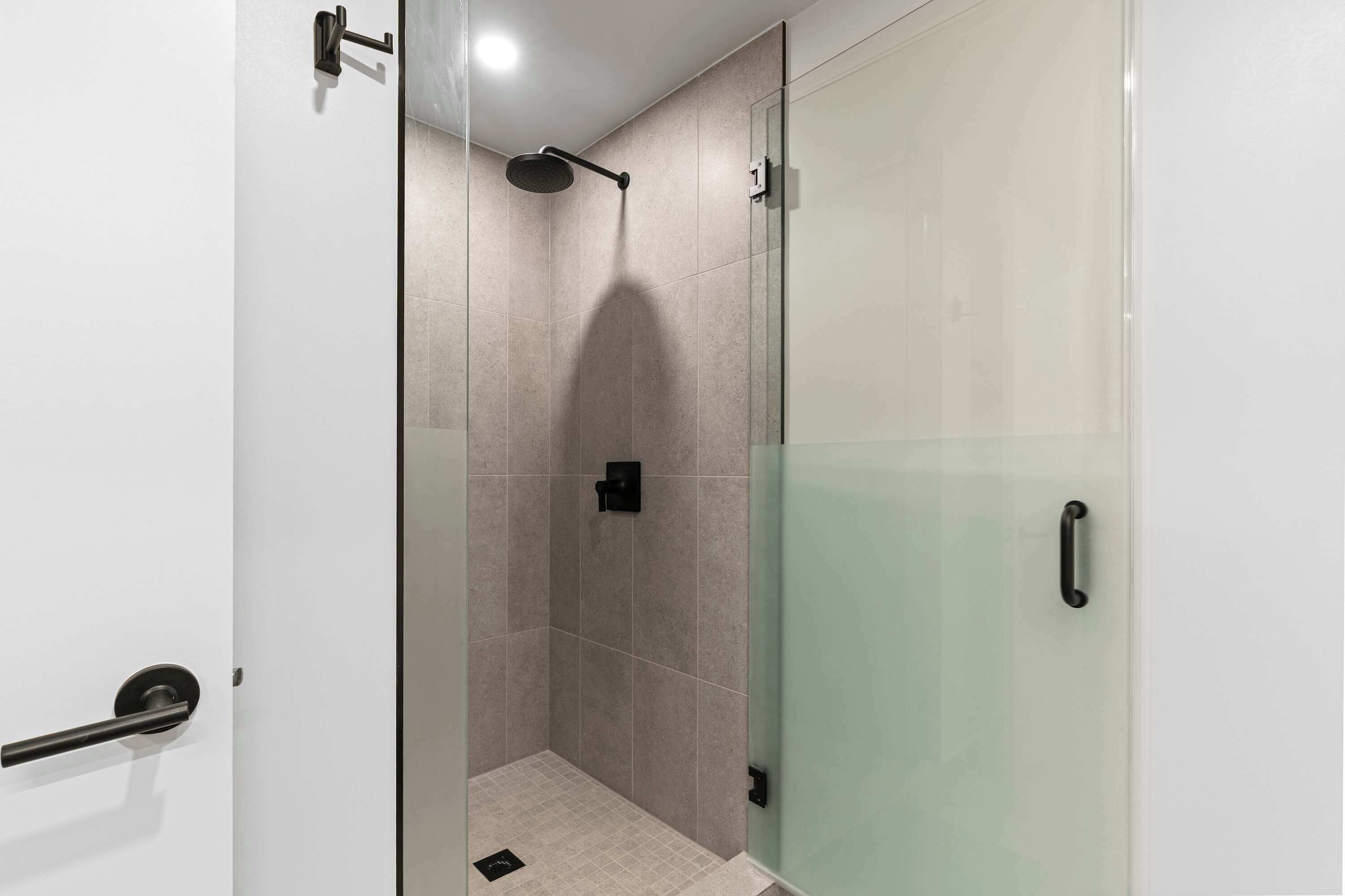 A modern bathroom with a glass shower enclosure, a towel rack, and a toilet.