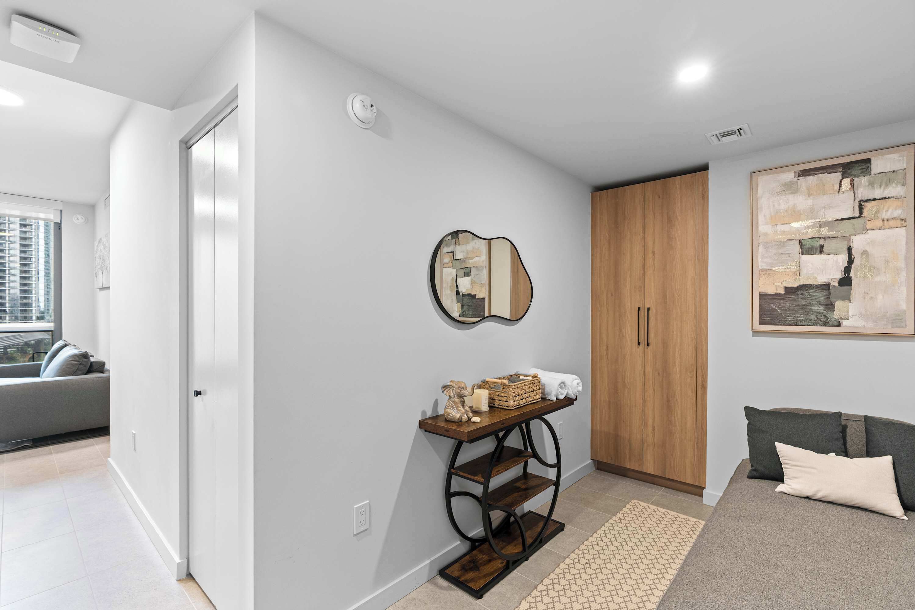 Un salon moderne avec un canapé gris, un meuble en bois et un miroir décoratif.