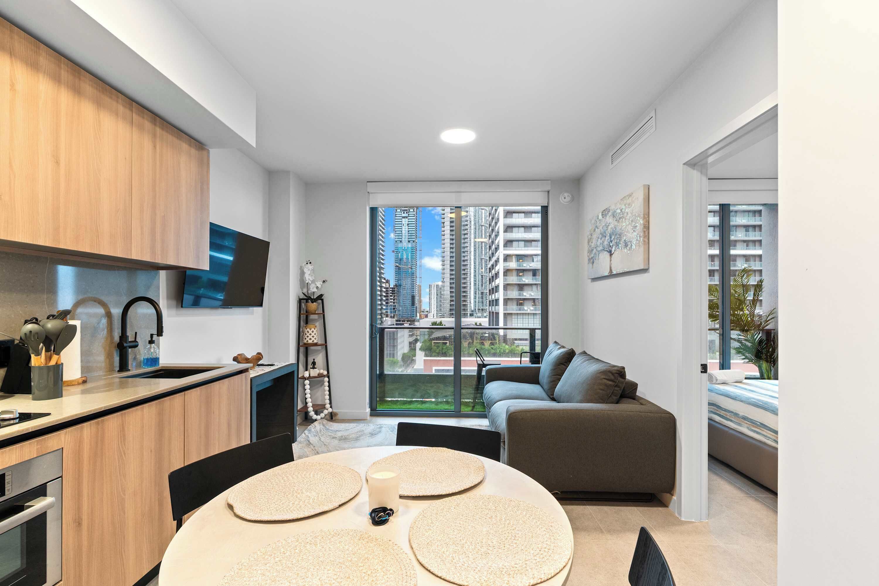 Een modern appartement met keuken, eethoek en woonkamer, met een groot raam en uitzicht over de stad.