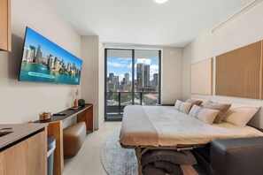 Ein modernes Hotelzimmer mit Blick auf die Stadt, inklusive Bett, Schreibtisch und Fernseher.