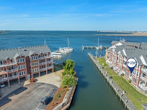 A waterfront property with multiple-story buildings, a marina with boats, and a clear view of the water. - Surf's Up: Waterfront | Shared Pool | Dogs OK (Manteo)