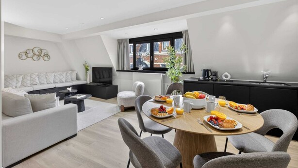 A modern living room with a sofa, TV, and dining area with breakfast.