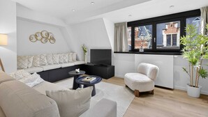 A modern living room with a sofa, armchair, coffee table, and a TV.