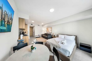 Ein modernes Hotelzimmer mit Bett, Esstisch, Küchenzeile und Wohnbereich.