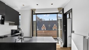 Una cocina moderna con una isla grande, horno empotrado y vistas a la ciudad a través de amplios ventanales.