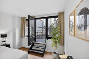 Ein Hotelzimmer mit Bett, Schreibtisch, Stuhl, einer Zimmerpflanze und einer Treppe, die zu einem Außenbereich führt.
