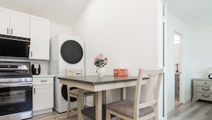 A modern kitchen with white cabinetry, a built-in oven, a microwave, and a coffee machine.