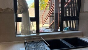 A kitchen with a window, a sink, and a metal drying rack. - One Bedroom Modern Apartment in Fomona - 2386 (Bulawayo)