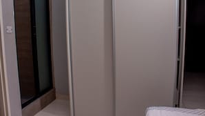 Quarto com porta deslizante, cama com colcha estampada e piso ladrilhado.