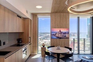 Een moderne keuken met een groot raam, een eethoek met een tafel en stoelen, en uitzicht op de stad.
