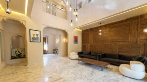 A spacious living area with a marble floor, a sofa set, a bench, and a wooden accent wall. - Villa Aurea (Marrakech)