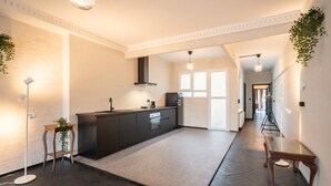 A modern kitchen with a central island, dark cabinetry, and a herringbone floor pattern. - 2BR City Stay - Grand Central Area (Antwerp)