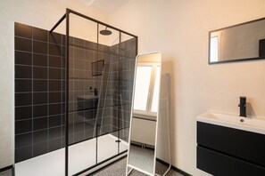 A modern bathroom with a glass shower enclosure, a white sink, and a mirror. - 2BR City Stay - Grand Central Area (Antwerp)