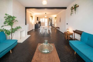 A spacious living area with a wooden coffee table, two sofas, a dining table, and a kitchen in the background. - 2BR City Stay - Grand Central Area (Antwerp)