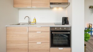 Eine moderne Küche mit Holdekor, einer Edelstahl-Spüle, einer Kaffeemaschine und einem Backofen.