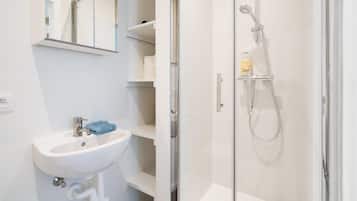 A bathroom with a glass-enclosed shower, a white sink, and a mirror.