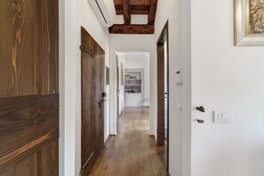 A hallway with wooden doors and a tiled floor leading to a room with a tiled backsplash and a framed picture on the wall. - 'Grimilda' Apartment with Shared Pool, Wi-Fi and Air Conditioning (Piombino Dese)