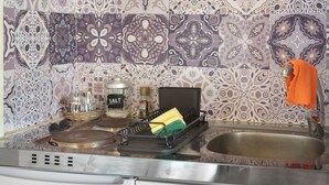 Una cocina con estufa, lavamanos y diferentes utensilios.