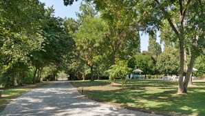 Un sendero de grava que serpentea por un parque con árboles y un pabellón a lo lejos.