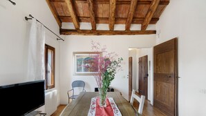 Un comedor con una mesa, sillas, un florero con flores, un cuadro en la pared y una puerta de madera.