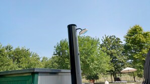Kirkas taivas, jossa näkyy metallipylväs ja siihen kiinnitetty suihkupää.