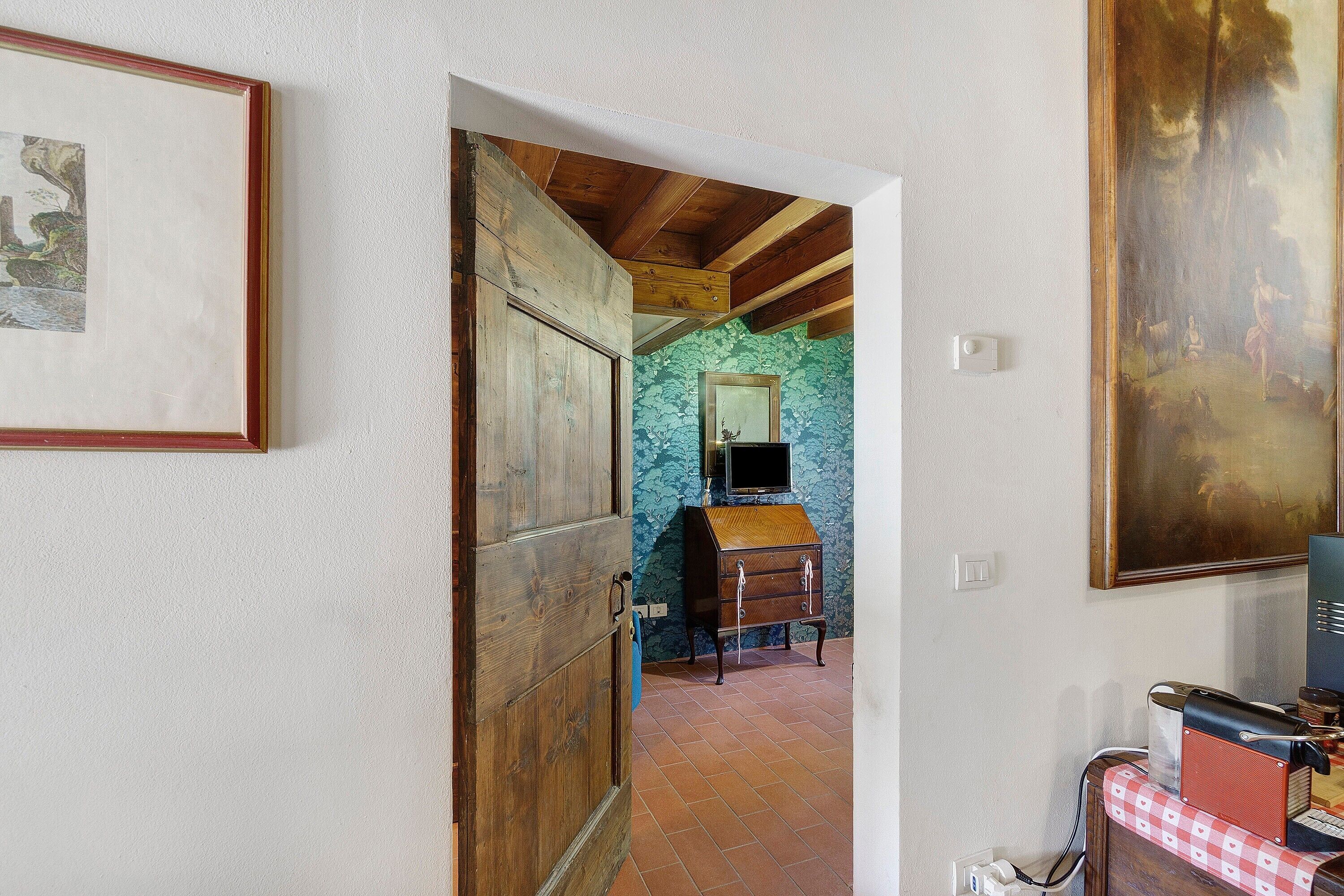 A room with a wooden door, a dresser, a mirror, and a painting on the wall.