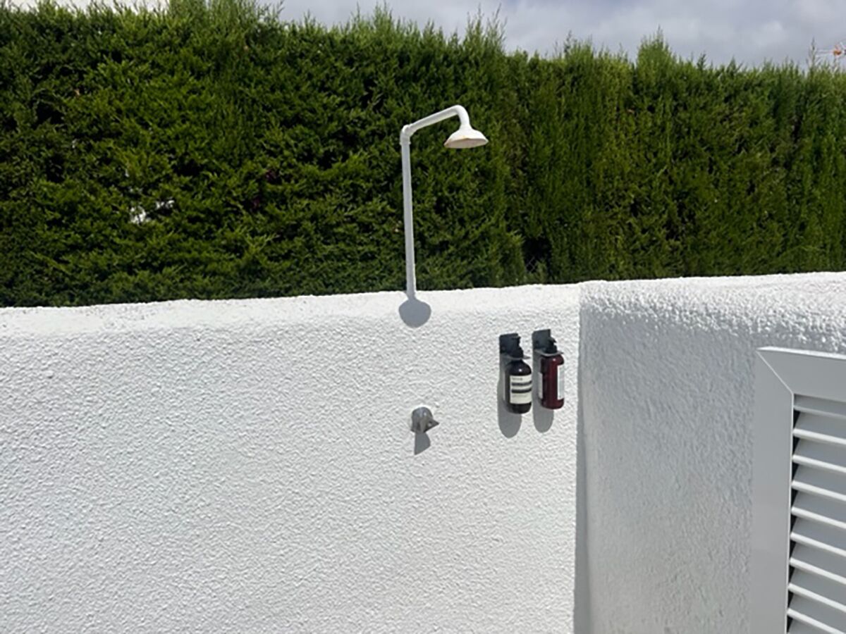 A white wall with a white lamp, two bottles, and a white door.