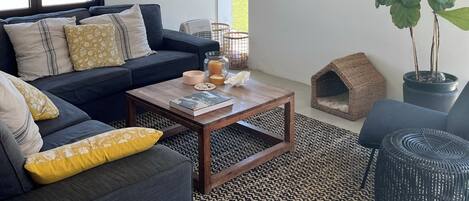 Una sala de estar moderna con un sofá, una mesa de centro, televisor, ventilador de techo y una planta en maceta.