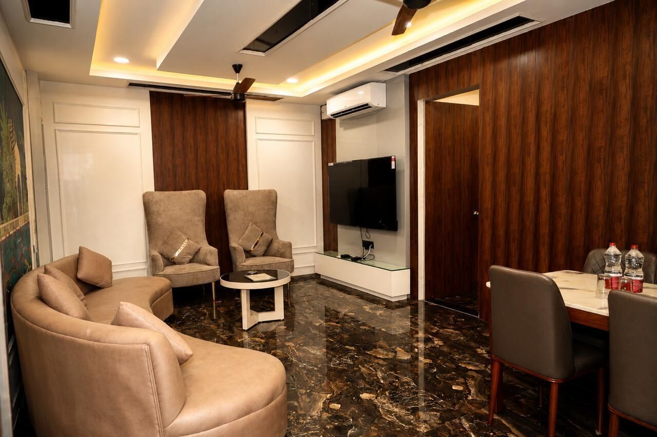 Una sala moderna con un sofá, sillones, una mesa de centro, un televisor y un comedor con sillas y una mesa.