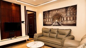 A living room with a leather sofa, a marble coffee table, a flat-screen TV, and a large framed picture on the wall.