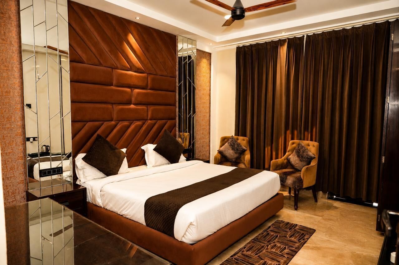 Une chambre d’hôtel moderne dotée d’un grand lit, d’un ventilateur de plafond, d’un miroir et offrant une vue sur l’extérieur.