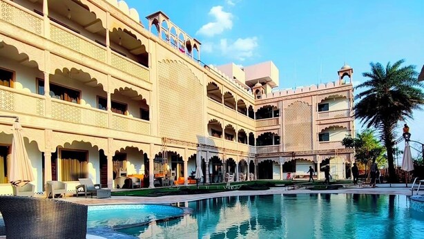 A hotel with a large pool, multiple balconies, and a traditional architectural style.