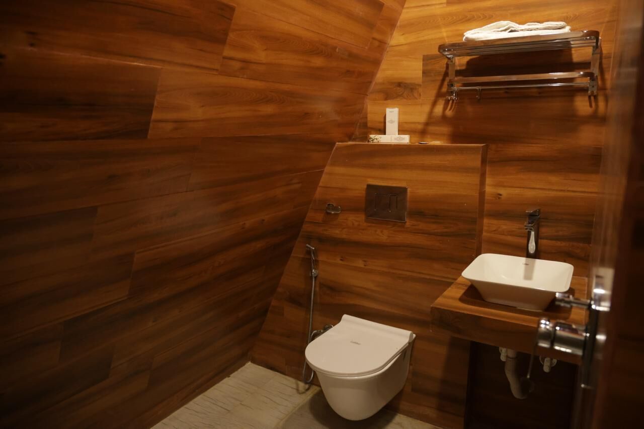 A wooden-paneled bathroom with a toilet, sink, and towel rack.