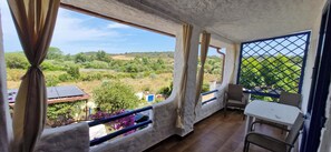 A balcony with a view of a green landscape, a table, and chairs. - Authentic Sardinian villa in nature within walking distance of a beautiful beach (Siniscola)