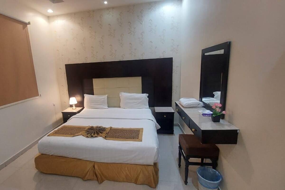 Une chambre d’hôtel comprenant un lit, une table de chevet, une chaise, un bureau et un miroir.