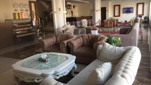A lobby with a reception desk, a staircase, a television screen, and a seating area with a coffee table. - Quiet Rooms 2   (Riyadh)