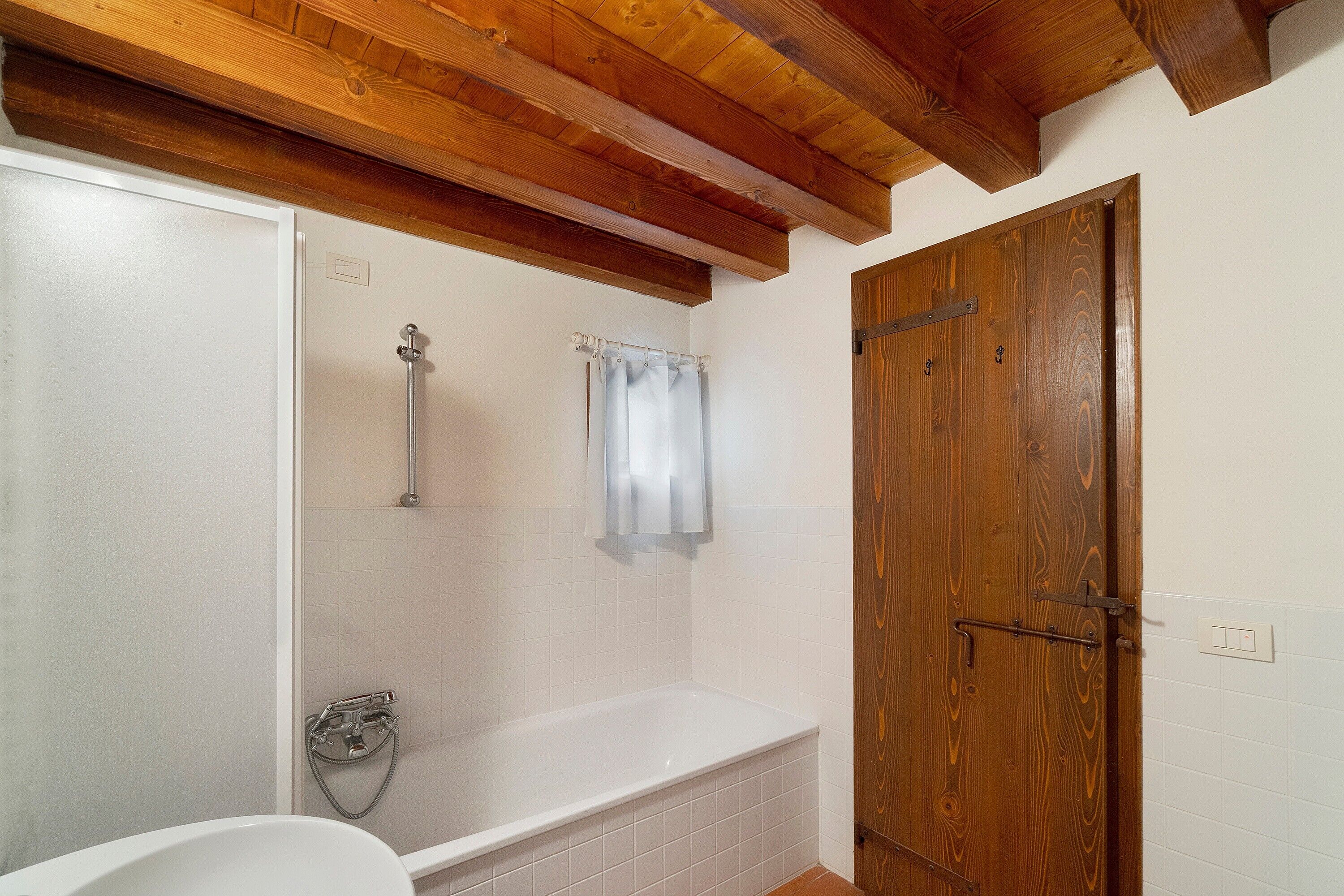 Un baño con ducha, bañera y puerta de madera.