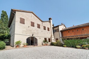 A building with a gravel driveway, a wooden door, and potted plants.