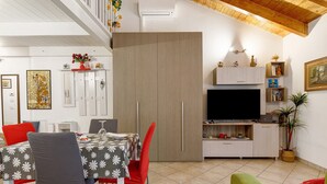 A dining area with a table set for two, a television, and a kitchenette. - Holiday Home 'Dimora Chiaretta' with Balcony, Wi-Fi and Air Conditioning (Caronno Pertusella)