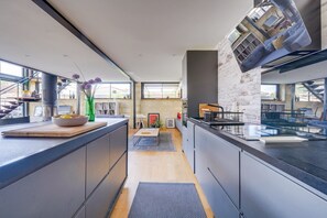 A modern kitchen with a long counter, a central island, and a view of the living area.
