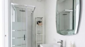 A modern bathroom with a glass shower enclosure, a white vanity with a mirror, and a built-in shelf. - Central Budget Rooms (Bergamo)