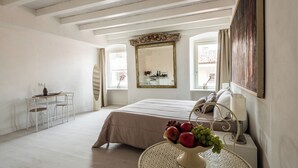 A bedroom with a bed, a table with fruit, a desk, and a mirror. - Central Budget Rooms (Bergamo)