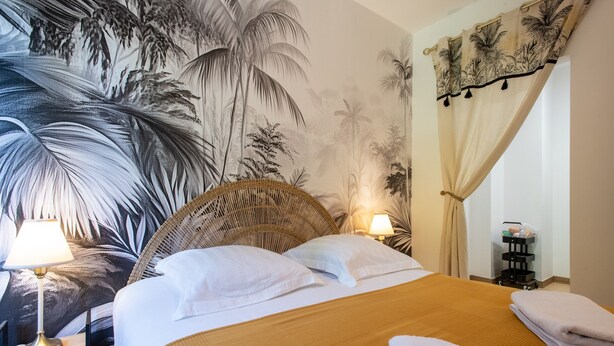 A hotel room with a bed, two bedside lamps, a wall mural, and a curtain. - Comme Un Pacha - Nausicaá & plage à 700 m (Boulogne-Sur-Mer)